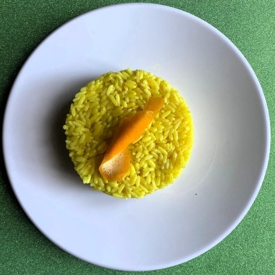Prato branco com arroz amarelo em círculo e casca de laranja