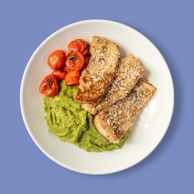 Prato com tofu ou seitan com sementes, purê verde e tomates cherry assados.