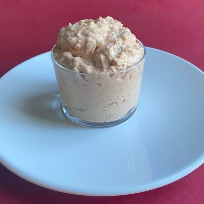 Pasta cremosa rosada num copo de vidro sobre prato branco e fundo vermelho