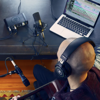 Pessoa gravando áudio com microfone, laptop e auscultadores