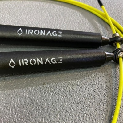 Corda de salto IRONAGE com cabos pretos e amarelo fluorescente sobre superfície cinza.