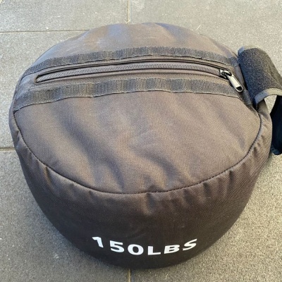 Saco de treino preto redondo com inscrição 150LBS e fecho de correr
