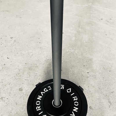 Disco de peso preto 15 KG IRONAGE sobre base metálica em chão de cimento
