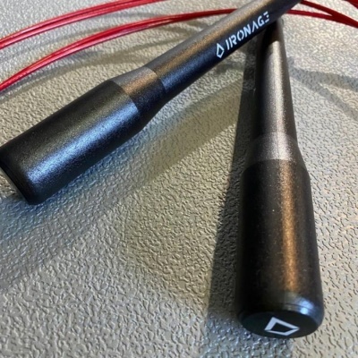 Corda de saltar com cabos pretos e cabo vermelho sobre superfície cinzenta