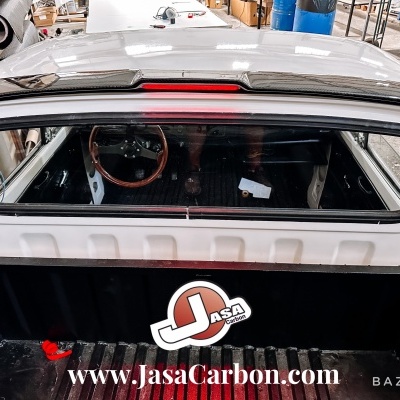 Parte traseira de carrinha branca com tejadilho em fibra de carbono com logotipo e texto promocional