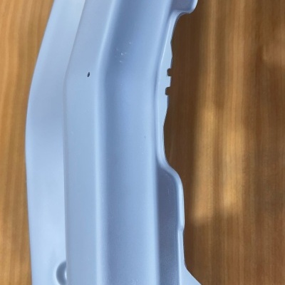 Componente de plástico cinzento claro sobre madeira clara