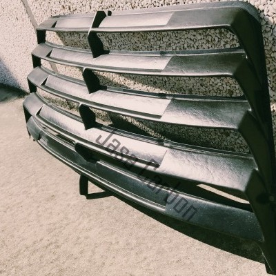 Grelha dianteira preta em plástico com acabamento fosco encostada em parede texturada