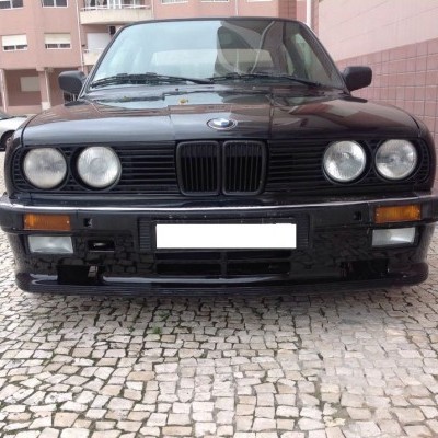 Frontal de automóvel preto BMW com faróis duplos e placa branca