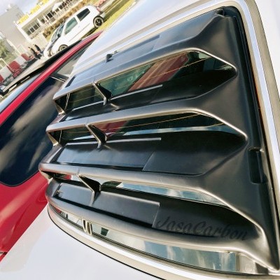 Persiana preta para janela lateral de carro branco, ao lado de carro vermelho num parque ao ar livre