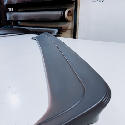 Spoiler traseiro preto em plástico com superfície lisa e linhas moldadas