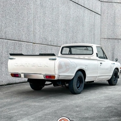 Pick-up branca Datsun num estacionamento com paredes cinza