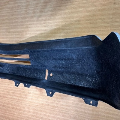 Peça automóvel preta de plástico em superfície de madeira clara