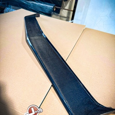 Spoiler de carbono preto sobre superfície clara em ambiente industrial