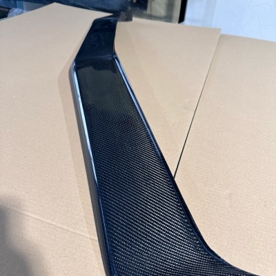 Spoiler aerodinâmico preto em carbono com padrão de fibra visível sobre cartão