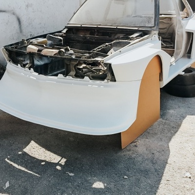Carro em restauro com carroçaria branca e interior desmontado num espaço exterior