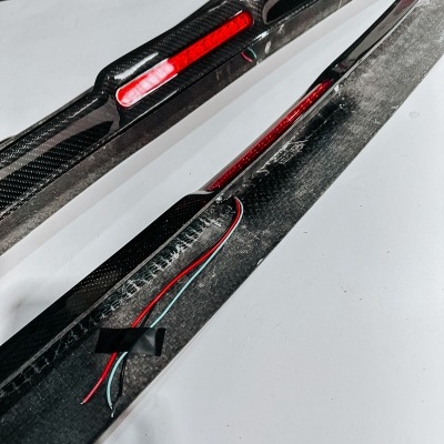 Peças de fibra de carbono com painéis LED vermelhos e fios expostos sobre superfície branca