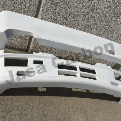 Para-choques dianteiros de plástico branco sobre chão cinza junto a parede