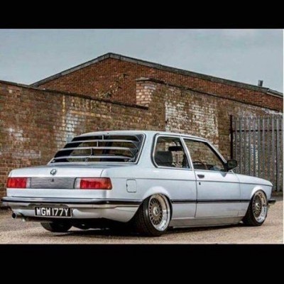 Carro clássico cinza claro com jantes prateadas e vidros traseiros com grade preta