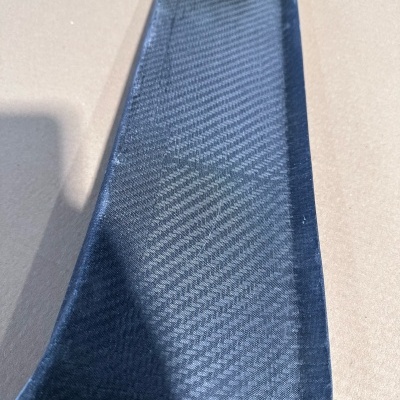 Peça de carbono preta com padrão visível e texto www.Jasacarbon.com