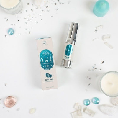 Frasco e caixa de produto cosmético com rótulo azul e branco em fundo branco com velas e cristais