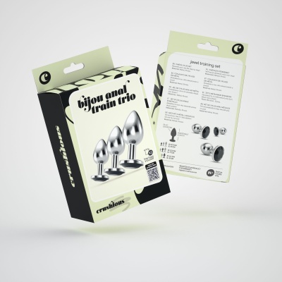 Embalagem em tons verde claro, preto e bege com três plugs anais metálicos e texto explicativo em inglês