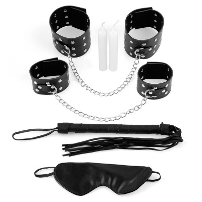 Conjunto de acessórios BDSM com algemas pretas e correntes, velas brancas, chicote preto e venda preta