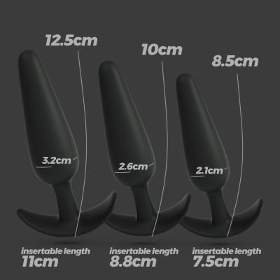 Três plugues anais pretos com medidas de altura e diâmetro indicadas, sobre fundo cinzento escuro