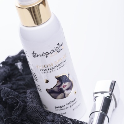 Frasco spray branco com rótulo e batom vermelho sobre renda preta