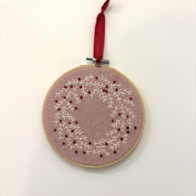 Bordado redondo rosa com coroa bordada em branco e vermelho pendurado com fita vermelha