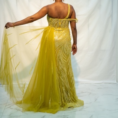 Vestido amarelo com um ombro só e capa de tule brilhante, visto de costas.