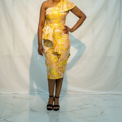 Vestido midi amarelo com padrão floral e sandálias pretas em fundo branco