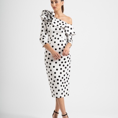 Vestido branco com bolinhas pretas com detalhe de flor grande no ombro e sandálias pretas