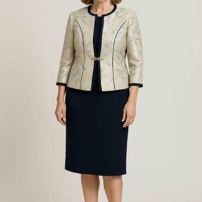 Mulher a usar vestido azul escuro e blazer bege com padrão floral e sapatos pretos.