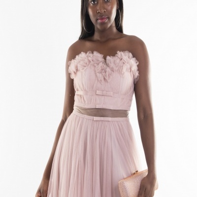 Mulher com vestido rosa claro e carteira pequena rosa