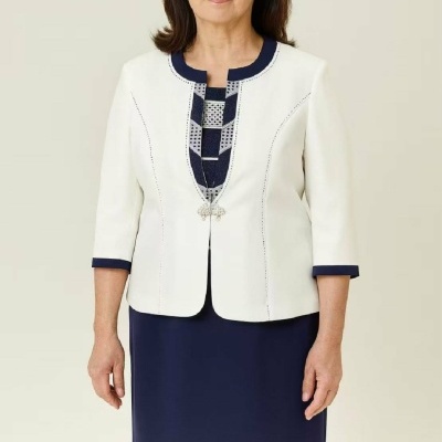 Mulher com vestido azul escuro e casaco branco com detalhes em azul escuro