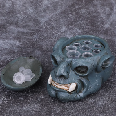 Cabeça de monstro cinzenta com copos transparentes no topo e base aberta ao lado