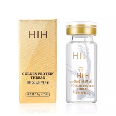 Frasco de vidro com fios brancos e embalagem dourada com texto em inglês e chinês