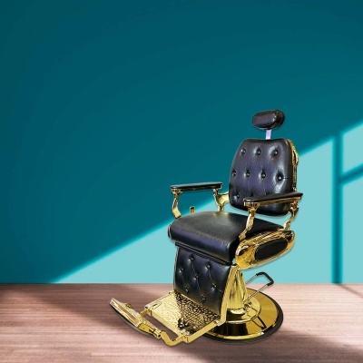 Cadeira de barbeiro preta com detalhes dourados e apoio para pés em ambiente com parede azul e piso em madeira