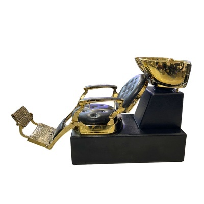 Cadeira de barbeiro dourada com almofada preta e lavatório dourado numa base preta