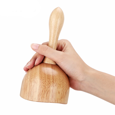 Utensílio de cozinha em madeira claro segurado por uma mão, fundo branco