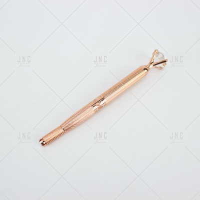 Caneta dourada com textura e ponta com pedra tipo diamante