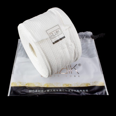 Rolo de tecido branco com etiqueta REJAK sobre saco transparente de armazenamento.