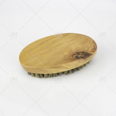 Escova oval de madeira clara com cerdas curtas sobre fundo branco