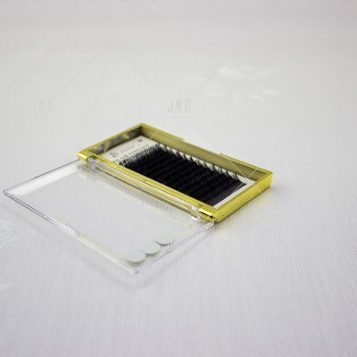 Caixa amarela com pestanas postiças pretas e tampa transparente aberta