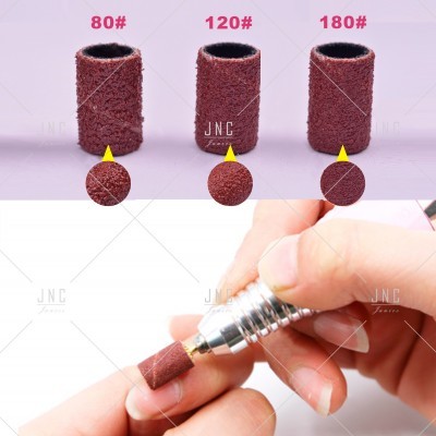 Três cilindros abrasivos castanhos com diferentes granulações e mão segurando dispositivo com cilindro encaixado