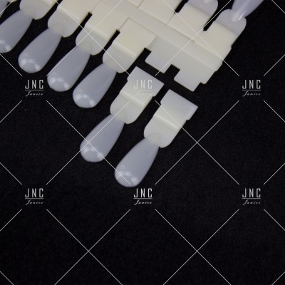 Paletas de unhas artificiais em plástico branco sobre fundo preto.