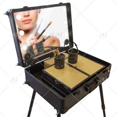 Mala de maquilhagem preta com espelho iluminado e pincéis em recipientes metálicos