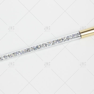 Pincel de maquilhagem com cabo transparente e brilhantes e punho dourado.