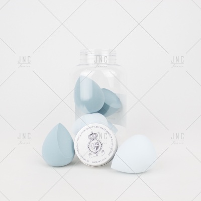 Frasco com esponjas de maquilhagem azuis e branca em formato gota com selo branco