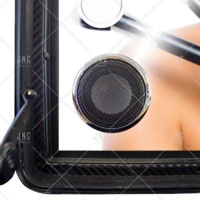 Altifalante redondo preto com moldura metálica prateada num painel preto texturizado